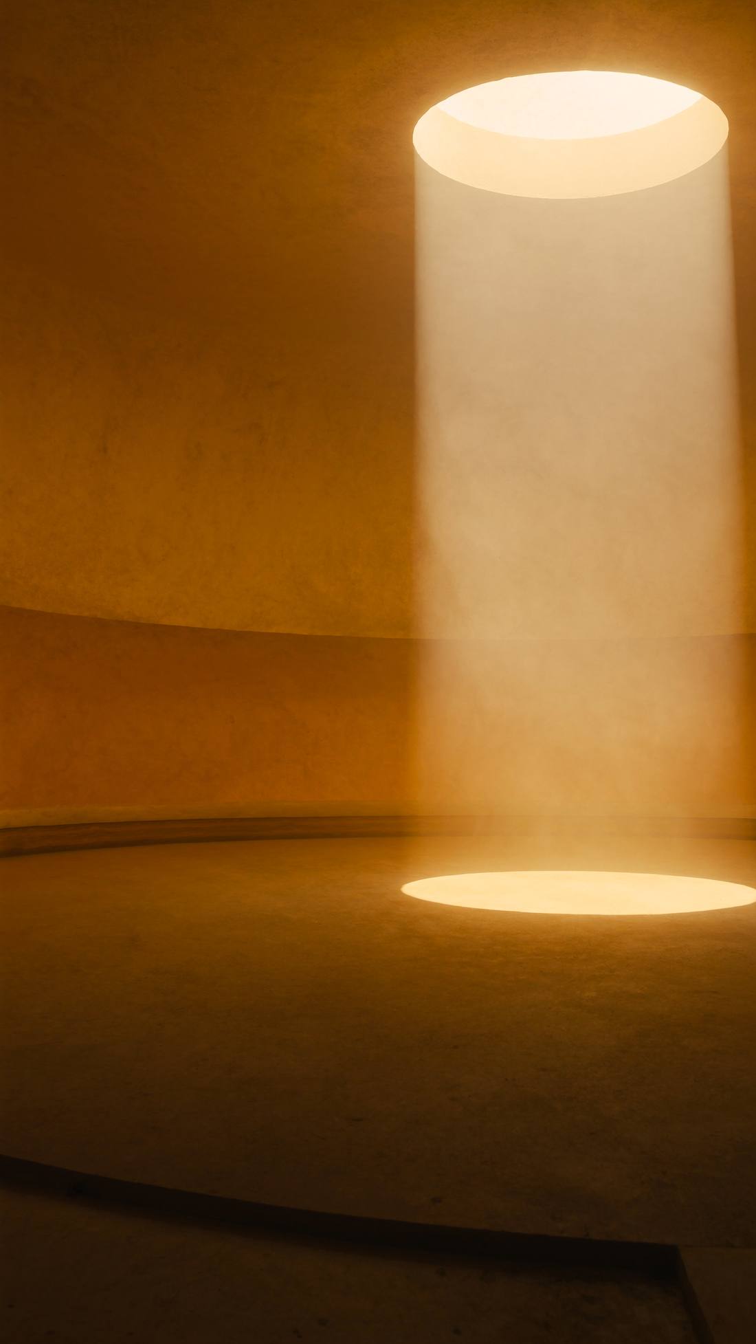 An ochre chamber with a column of daylight falling through an oculus.